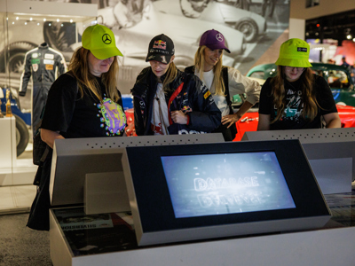 A group of young women interact with the touch screens at Silverstone Museum in the Tech Lab