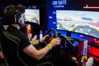 P1 Podcast Host Matthew Gallagher driving the Sim Suite at Silverstone Museum, looking at the wide-screen with his hands on the steering wheel and feet on the pedals.